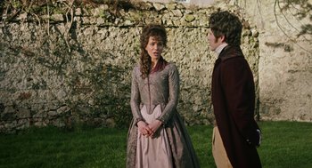 Movie still from “Love & Friendship” (2016), directed by Whit Stillman – A woman in a long dress standing next to a man in a jacket; Medium shot, Over the shoulder angle