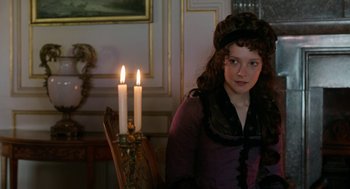 Movie still from “Love & Friendship” (2016), directed by Whit Stillman – A young girl in a purple dress with two lit candles; Medium shot, Over the shoulder angle