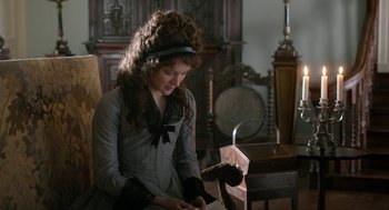 Movie still from “Love & Friendship” (2016), directed by Whit Stillman – A young woman in a victorian dress looking down at a book; Medium shot, High angle