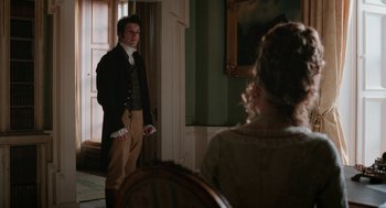 Movie still from “Love & Friendship” (2016), directed by Whit Stillman – A man and a woman are standing in front of a window; Medium shot, Over the shoulder angle