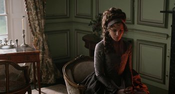 Movie still from “Love & Friendship” (2016), directed by Whit Stillman – A woman sitting on a chair in a room; Medium shot, High angle