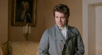 Movie still from “Love & Friendship” (2016), directed by Whit Stillman – A young man in a gray coat standing next to a painting; Medium shot, Over the shoulder angle
