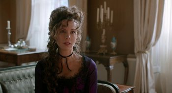Movie still from “Love & Friendship” (2016), directed by Whit Stillman – A woman with long curly hair sitting in front of a table; Close Up shot, Over the shoulder angle