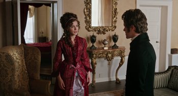 Movie still from “Love & Friendship” (2016), directed by Whit Stillman – A woman in a red dress talking to a man in a black suit; Medium shot, Over the shoulder angle