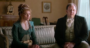 Movie still from “Love & Friendship” (2016), directed by Whit Stillman – Two people sitting on a couch in front of a window; Medium shot, Over the shoulder angle