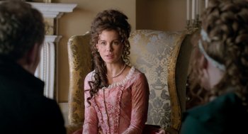 Movie still from “Love & Friendship” (2016), directed by Whit Stillman – A woman sitting in a chair wearing a pink dress; Close Up shot, Over the shoulder angle