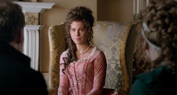Movie still from “Love & Friendship” (2016), directed by Whit Stillman – A woman sitting in a chair wearing a pink dress; Close Up shot, Over the shoulder angle