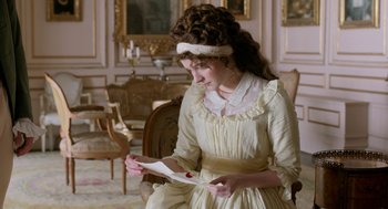 Movie still from “Love & Friendship” (2016), directed by Whit Stillman – A woman in a white dress is holding a paper; Medium shot, Over the shoulder angle