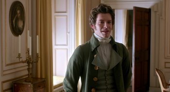 Movie still from “Love & Friendship” (2016), directed by Whit Stillman – A man in a green jacket standing next to a window; Medium shot, Over the shoulder angle