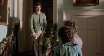 Movie still from “Love & Friendship” (2016), directed by Whit Stillman – A man standing in front of two other people; Medium shot, Over the shoulder angle