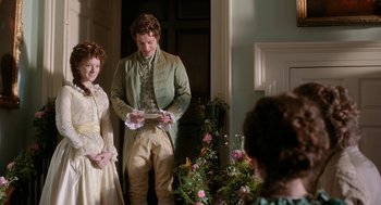Movie still from “Love & Friendship” (2016), directed by Whit Stillman – A man and a woman standing next to each other in front of flowers; Medium shot, Over the shoulder angle