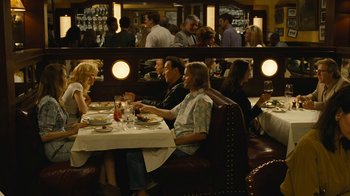 Movie still from “Love & Mercy” (2014), directed by Bill Pohlad – A group of people sitting at a table in a restaurant; Wide shot, Over the shoulder angle