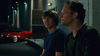 Movie still from “Love & Mercy” (2014), directed by Bill Pohlad – Two men sitting next to each other in front of a building; Medium shot, Over the shoulder angle