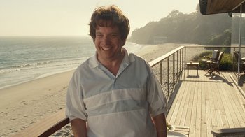 Movie still from “Love & Mercy” (2014), directed by Bill Pohlad – A man standing next to the ocean on a beach; Medium shot, Over the shoulder angle