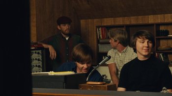 Movie still from “Love & Mercy” (2014), directed by Bill Pohlad – A group of people sitting around a table; Medium shot, Over the shoulder angle