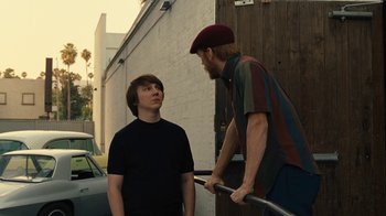 Movie still from “Love & Mercy” (2014), directed by Bill Pohlad – Two men standing next to each other near a building; Medium shot, Over the shoulder angle
