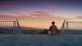 Movie still from “Love & Mercy” (2014), directed by Bill Pohlad – A man sitting on a ledge looking out at the mountains; Extreme Wide shot, Low angle