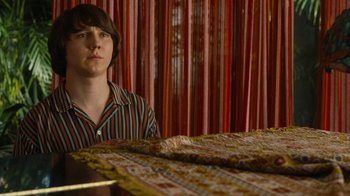 Movie still from “Love & Mercy” (2014), directed by Bill Pohlad – A man sitting in front of a table with a rug; Medium shot, Over the shoulder angle