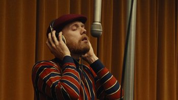 Movie still from “Love & Mercy” (2014), directed by Bill Pohlad – A man with a red hat is listening to headphones; Close Up shot, Low angle