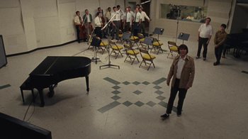 Movie still from “Love & Mercy” (2014), directed by Bill Pohlad – A man standing in front of an orchestra room; Wide shot, High angle