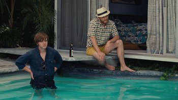 Movie still from “Love & Mercy” (2014), directed by Bill Pohlad – A man and a woman sitting on the edge of a swimming pool; Medium shot, High angle