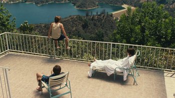 Movie still from “Love & Mercy” (2014), directed by Bill Pohlad – Three people sitting on a deck overlooking a lake; Wide shot, High angle