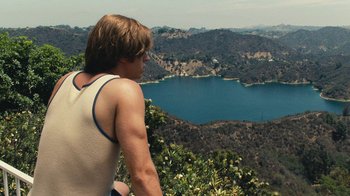 Movie still from “Love & Mercy” (2014), directed by Bill Pohlad – A man looking out over a body of water from a hill; Medium shot, High angle