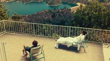 Movie still from “Love & Mercy” (2014), directed by Bill Pohlad – A man laying on top of a deck next to a lake; Extreme Wide shot, High angle