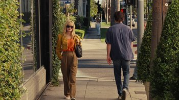 Movie still from “Love & Mercy” (2014), directed by Bill Pohlad – A woman walking down the street while a man walks by; Wide shot, Over the shoulder angle