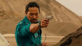 Movie still from “Machete Kills” (2013), directed by Robert Rodriguez – A man holding a gun while standing in the desert; Medium shot, Over the shoulder angle