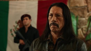 Movie still from “Machete Kills” (2013), directed by Robert Rodriguez – A man with long black hair wearing a brown jacket; Close Up shot, Over the shoulder angle