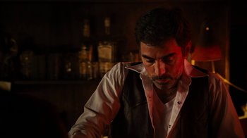 Movie still from “Machete Kills” (2013), directed by Robert Rodriguez – A man in white shirt and black vest standing in front of a bar; Medium shot, Low angle