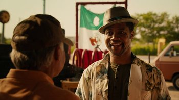 Movie still from “Machete Kills” (2013), directed by Robert Rodriguez – A man wearing a hat talking to another man in front of a flag; Close Up shot, Over the shoulder angle