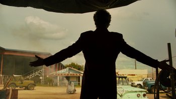 Movie still from “Machete Kills” (2013), directed by Robert Rodriguez – A man standing under an open umbrella in the rain; Wide shot, Low angle