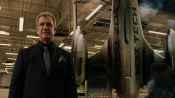 Movie still from “Machete Kills” (2013), directed by Robert Rodriguez – A man in a suit and tie standing in front of an airplane; Medium shot, Low angle