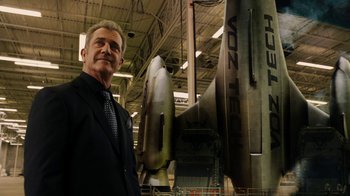 Movie still from “Machete Kills” (2013), directed by Robert Rodriguez – A man standing in front of an airplane in a hangar; Medium shot, Low angle