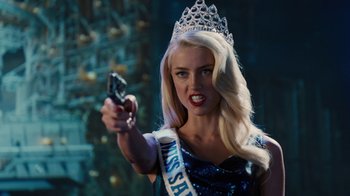 Movie still from “Machete Kills” (2013), directed by Robert Rodriguez – A woman in a tiara holding a gun in her hand; Close Up shot, Over the shoulder angle