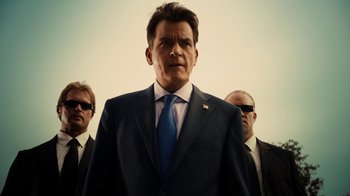 Movie still from “Machete Kills” (2013), directed by Robert Rodriguez – A man in a suit and tie standing next to two other men; Medium shot, Low angle