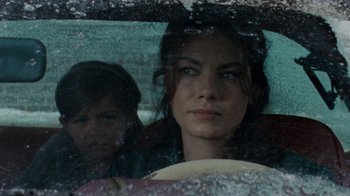 Movie still from “Machine Gun Preacher” (2011), directed by Marc Forster – A woman sitting in a car with a child in the back seat; Close Up shot, Over the shoulder angle
