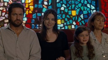 Movie still from “Machine Gun Preacher” (2011), directed by Marc Forster – A woman sitting next to a man and a girl; Medium shot, Over the shoulder angle