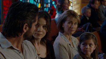 Movie still from “Machine Gun Preacher” (2011), directed by Marc Forster – A group of people sitting next to each other in front of a stained glass window; Close Up shot, Over the shoulder angle