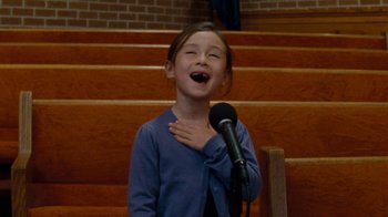 Movie still from “Machine Gun Preacher” (2011), directed by Marc Forster – A young girl standing in front of a microphone; Medium shot, Low angle