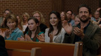Movie still from “Machine Gun Preacher” (2011), directed by Marc Forster – A group of people sitting and clapping in a church; Medium shot, Over the shoulder angle