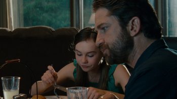 Movie still from “Machine Gun Preacher” (2011), directed by Marc Forster – A man and a little girl sitting at a dinner table; Medium shot, Over the shoulder angle