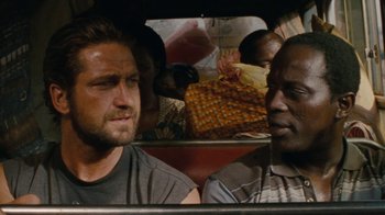 Movie still from “Machine Gun Preacher” (2011), directed by Marc Forster – Two men in the back of a car with people in the background; Close Up shot, Over the shoulder angle
