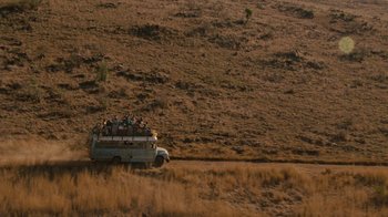 Movie still from “Machine Gun Preacher” (2011), directed by Marc Forster – An old bus is driving down a dirt road; Extreme Wide shot, High angle