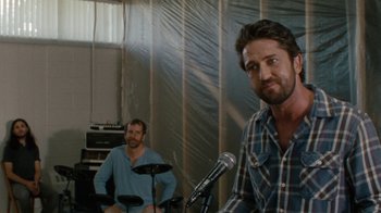 Movie still from “Machine Gun Preacher” (2011), directed by Marc Forster – Two men are sitting in front of microphones in a room; Medium shot, Over the shoulder angle