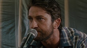Movie still from “Machine Gun Preacher” (2011), directed by Marc Forster – A person holding a microphone; Close Up shot, Low angle