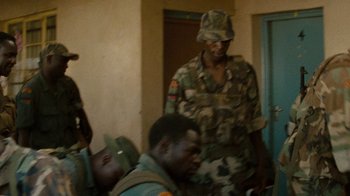 Movie still from “Machine Gun Preacher” (2011), directed by Marc Forster – A man in a military uniform standing next to another man in fatigues; Medium shot, Over the shoulder angle