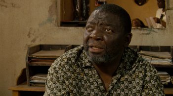 Movie still from “Machine Gun Preacher” (2011), directed by Marc Forster – An older black man wearing a patterned shirt; Close Up shot, Over the shoulder angle